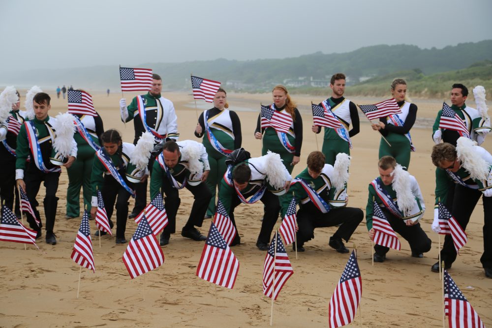 PNNMB members plant small American flags into the sand of Omaha Beach.